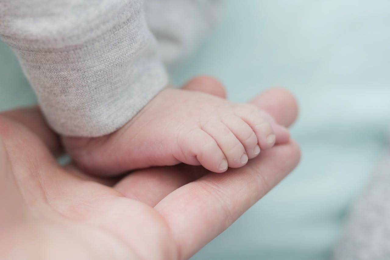 Tender moment capturing a newborn's tiny foot held by a gentle hand.